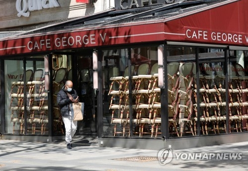 16일 프랑스 파리 샹젤리제 거리에서 마스크를 쓴 시민이 문닫은 카페 앞을 지나가고 있다, 사진=로이터/연합뉴스